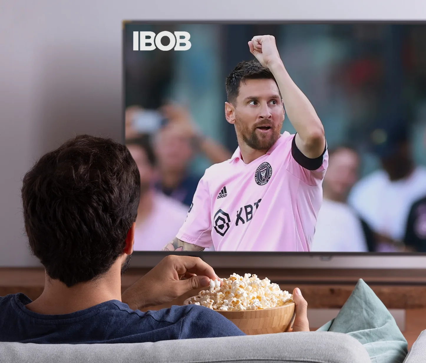 Fußball schauen auf dem Fernseher im Wohnzimmer, mit dem IBOB-Player-Logo auf dem Bildschirm